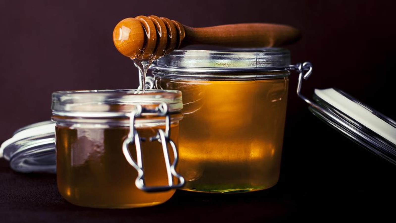 Glass jars of honey with a wooden honey dipper