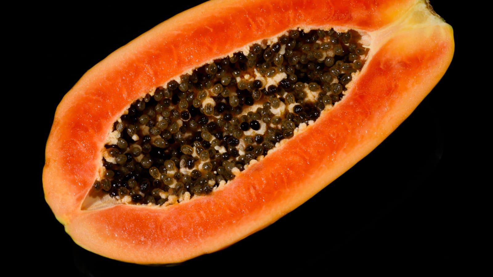 A halved ripe papaya showing orange flesh and dark seeds